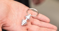 Nahaufnahme der Hand einer Person, auf der ein Schlüsselanhänger mit einer kleinen Hantel liegt