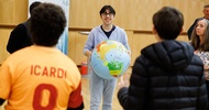 Mehrere Personen stehen in einem Kreis. Eine Person hält einen Ball, auf dem die Erde abgebildet ist