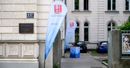 Vor der Fassade eines Hauses steht ein Werbebanner, auf dem Berufsinfozentrum und biwi.at steht. Auf der Fassade ist eine Plakette, auf der Berufsschule für Friseure steht