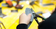 Nahaufnahme der Hände einer Person, die ein flaches Metallstück mit einer Metallschere schneidet