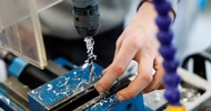 Nahaufnahme eines vertikalen Metallbohrers. Neben dem Bohrer ist die Hand einer Person