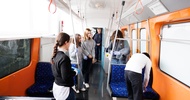 In einer leeren, stehenden U-Bahn stehen mehrere Personen. Ein paar der Personen tragen Handschuhe