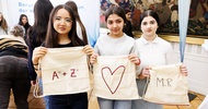 Porträt dreier nebeneinander stehender Teenager, die jeweils ein helles Stoffsackerl in den Händen halten. Auf den Stoffsackerln sind Sachen eingestickt, zum Beispiel ein Herz