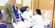 Personen stehen um einen Behandlungsstuhl mit Testperson