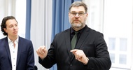 Person in dunklem Anzug spricht vor Teilnehmenden