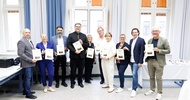 Gruppe hält Urkunden in einem Seminarraum