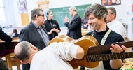  Eine Person hält eine Gitarre in die Luft. Eine andere Person steht vor der Gitarre