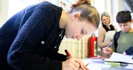 Eine Person malt mit einem Stift etwas auf einem Blatt Papier