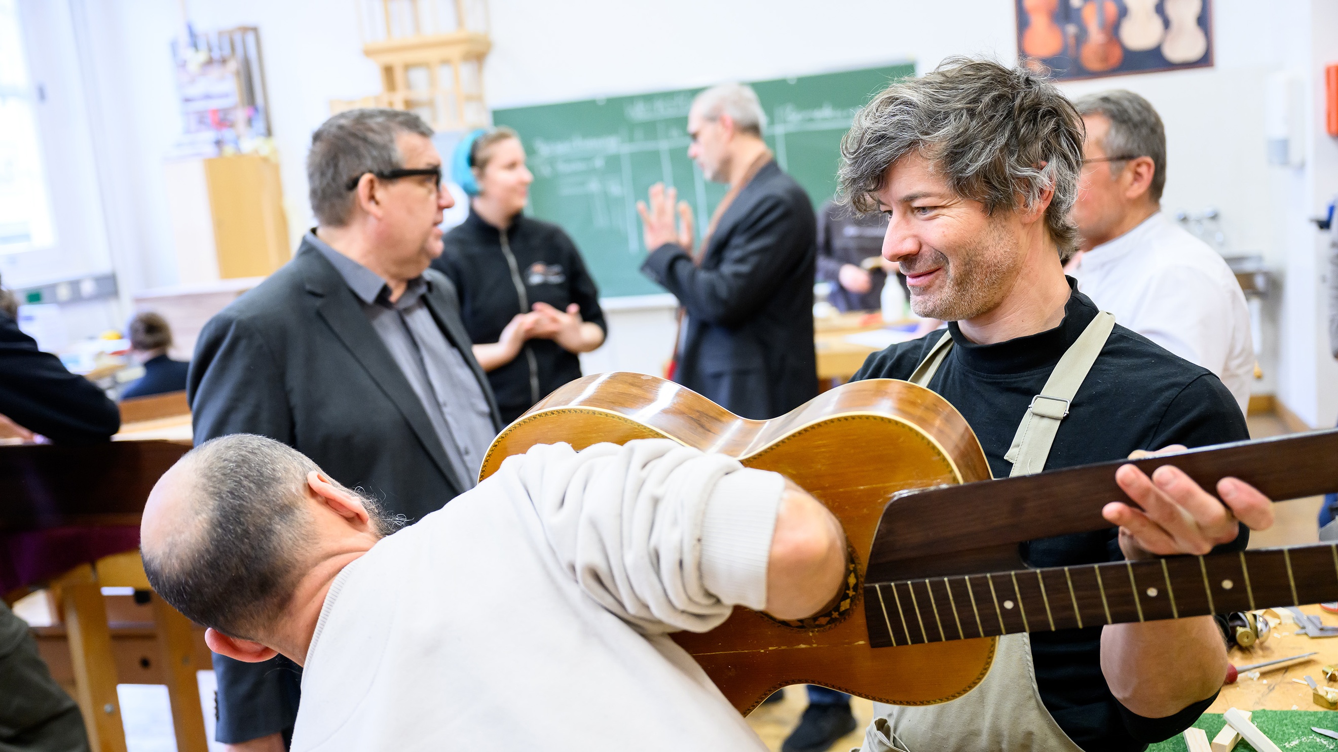  Eine Person hält eine Gitarre in die Luft. Eine andere Person steht vor der Gitarre