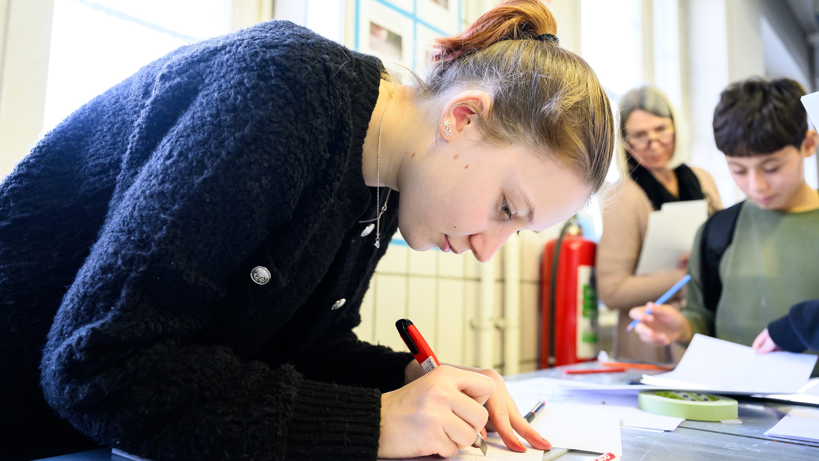 Eine Person malt mit einem Stift etwas auf einem Blatt Papier