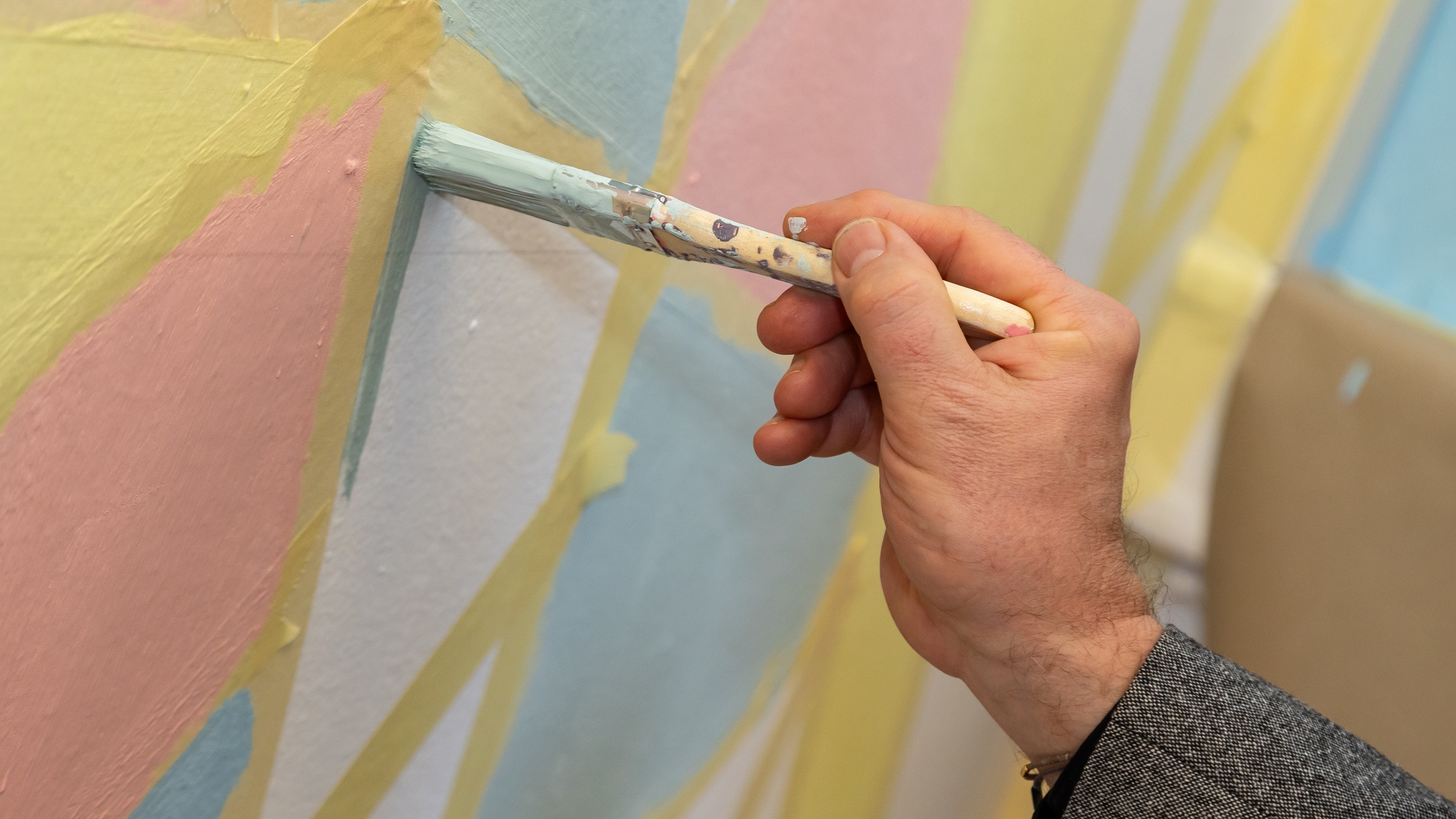 Nahaufnahme einer Person, die mit einem Pinsel auf einer Wand malt