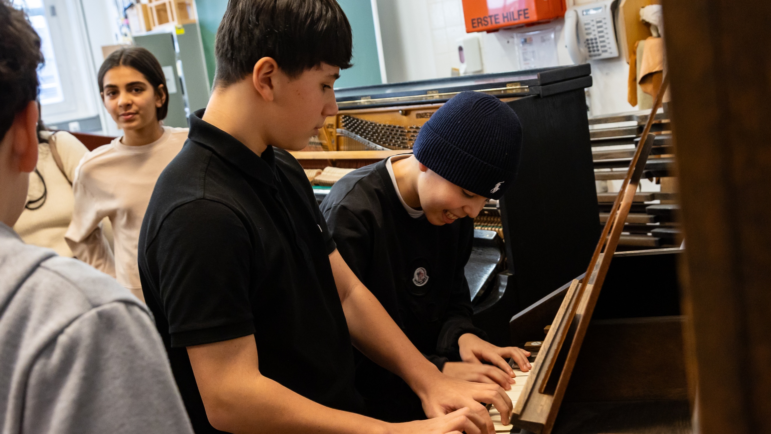 Zwei jugendliche Personen spielen auf einem Klavier