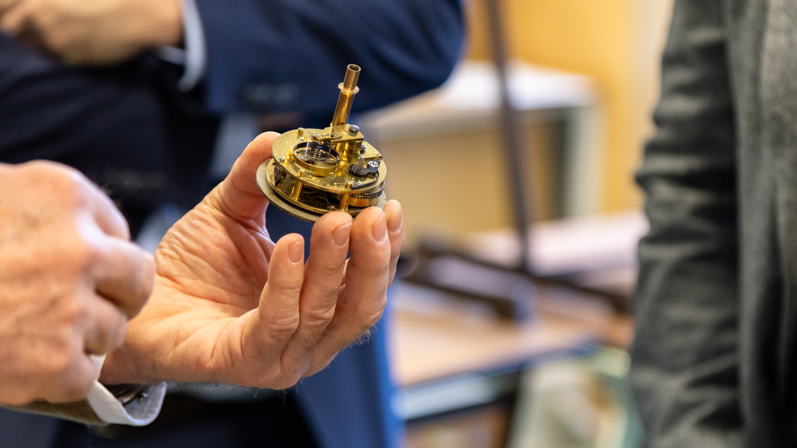 Nahaufnahme der linken Hand einer Person, die ein Uhrwerk hält