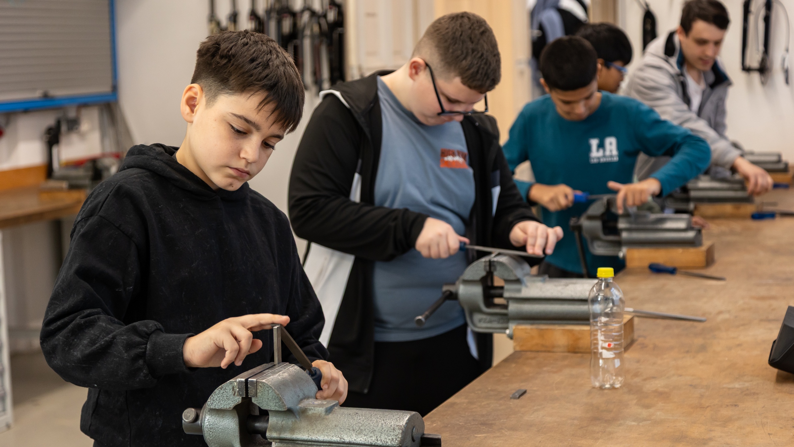 Fünf jugendliche stehen nebeneinander an einem Tisch mit Drehbänken und probieren diese aus