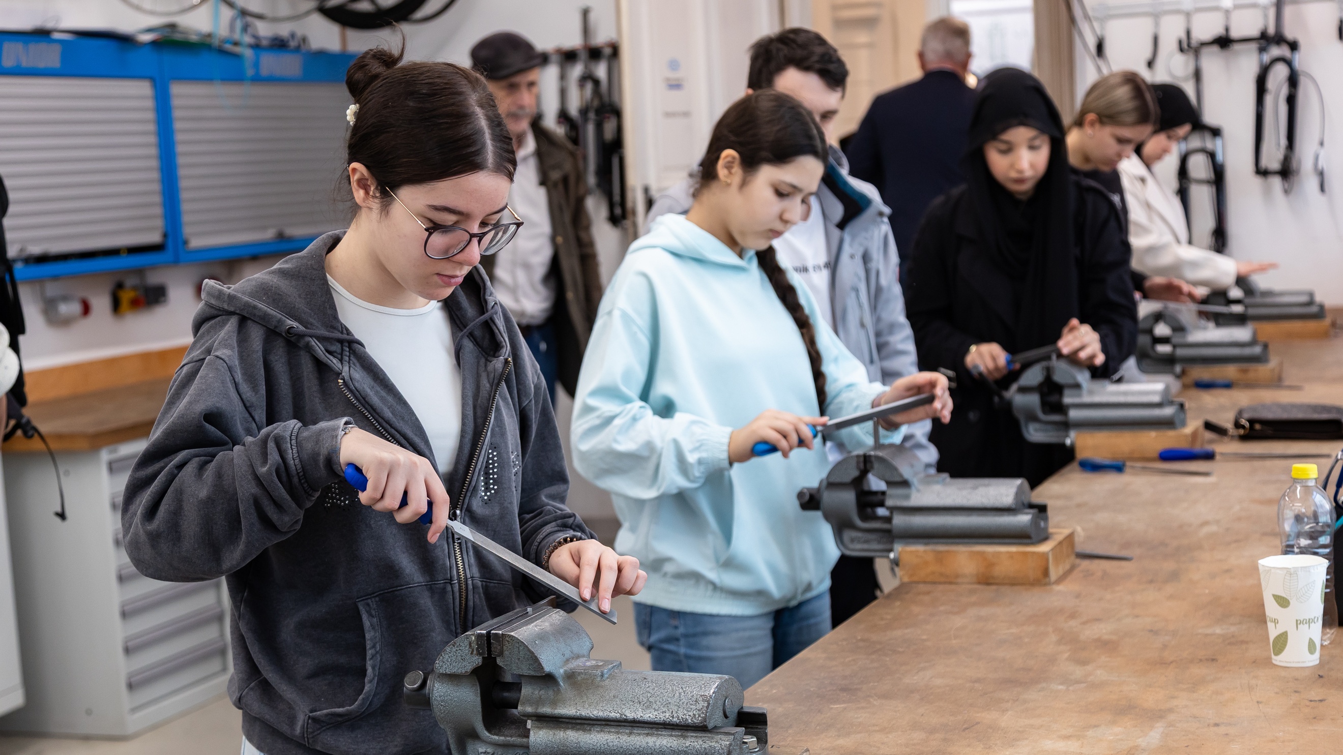 Fünf jugendliche stehen nebeneinander an einem Tisch mit montieren Schleifmaschinen und probieren diese aus