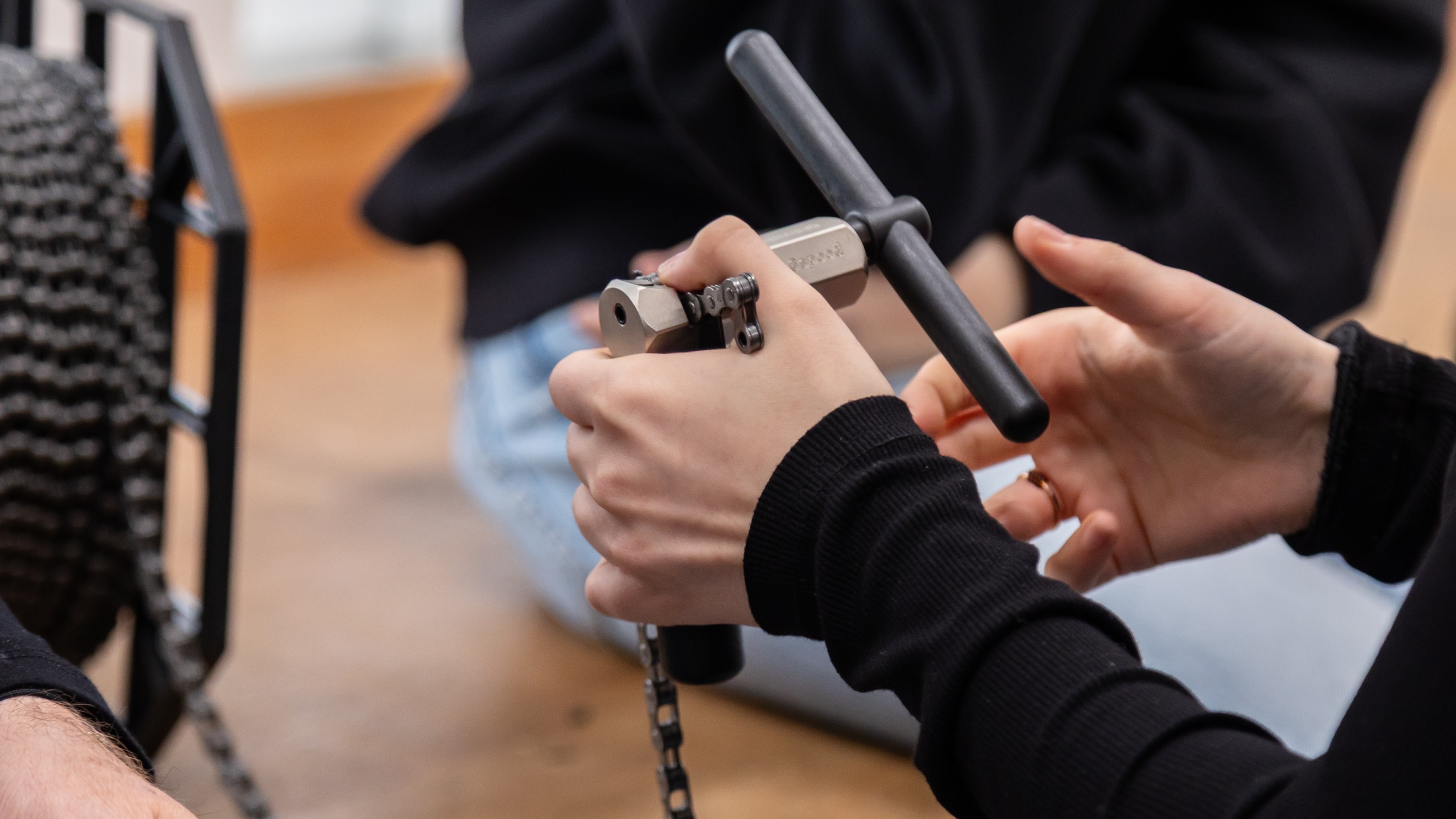 Nahaufnahme der Hände einer Person, die ein Werkzeug zum Aufwicklen einer Metallschnur ausprobiert