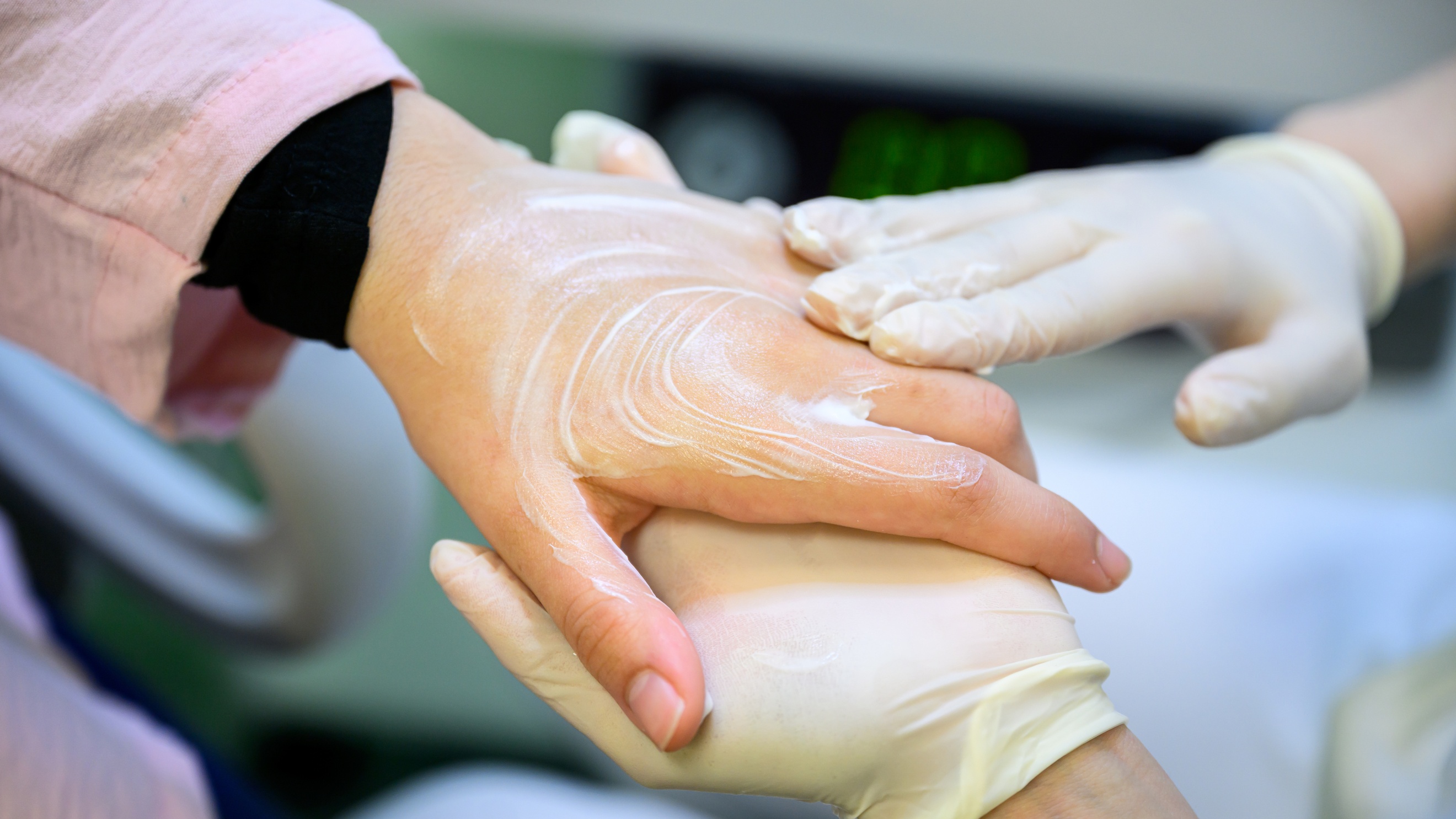 Nahaufnahme der Hand einer Person, die von den Händen einer anderen Person eingecremt wird