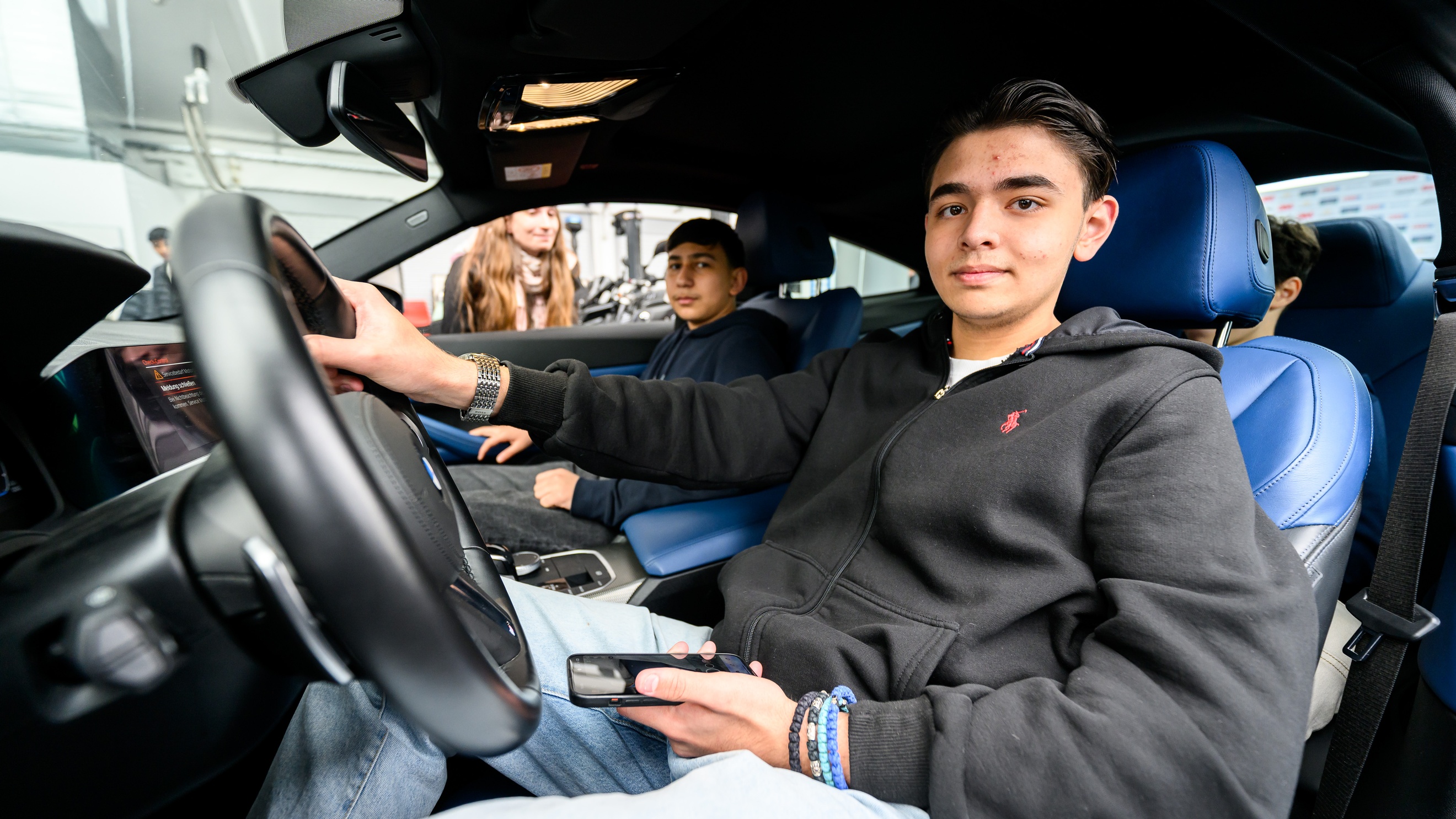 Am Steuer eines Autos, am Beifahrersitz sowie auf der Rückbank sitzen Jugendliche